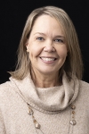 Woman wearing brown sweater smiles 